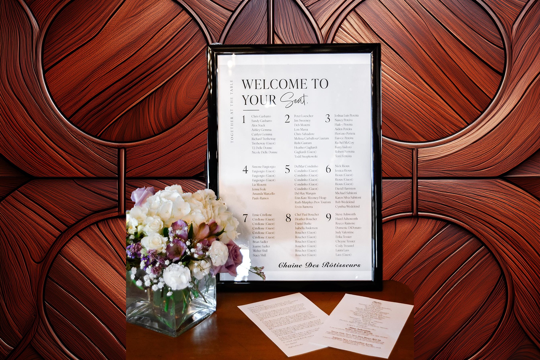 Elegant wedding seating chart sign in black frame with floral arrangement showcasing OptiPrint's professional event signage and custom printing services